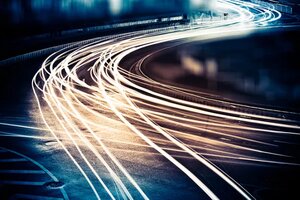 A photo of a road at night, taken with long shutter speed, making the headlights of the cars look like bright lines