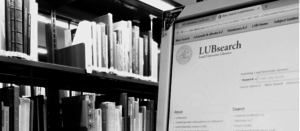 Dator med LUBsearch öppet och bokhylla i bakgrunden