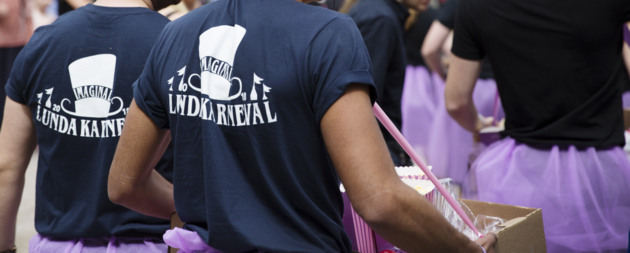 Bild på två personers ryggar. Personerna bär mörkslå Lundakarnevalströjor.